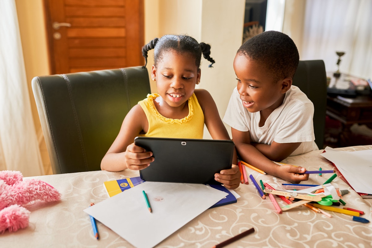 two siblings sit side by side using a tablet